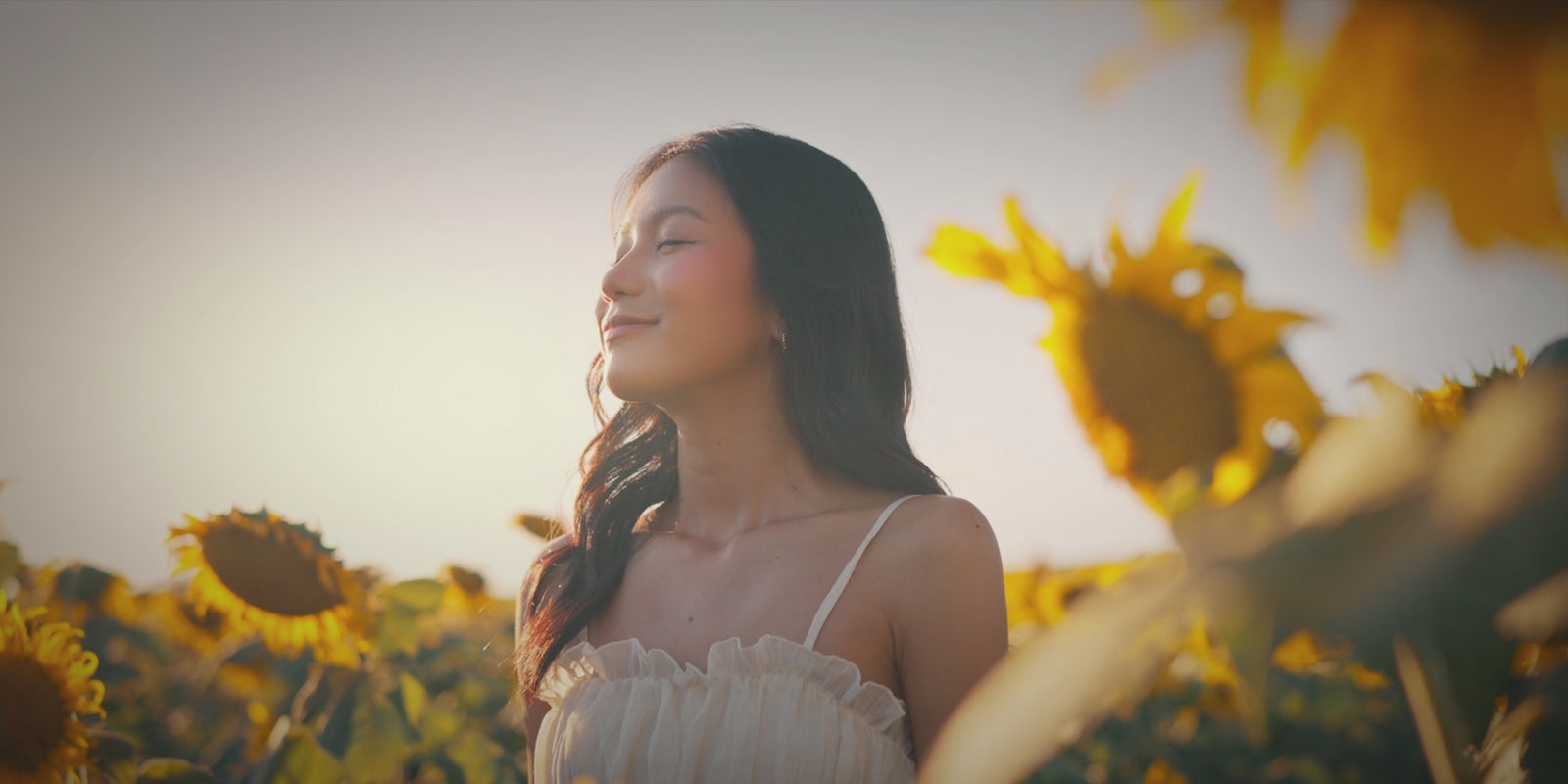 Reboot. Happy woman in her 20s in a field taking in a deep breath and smiling.