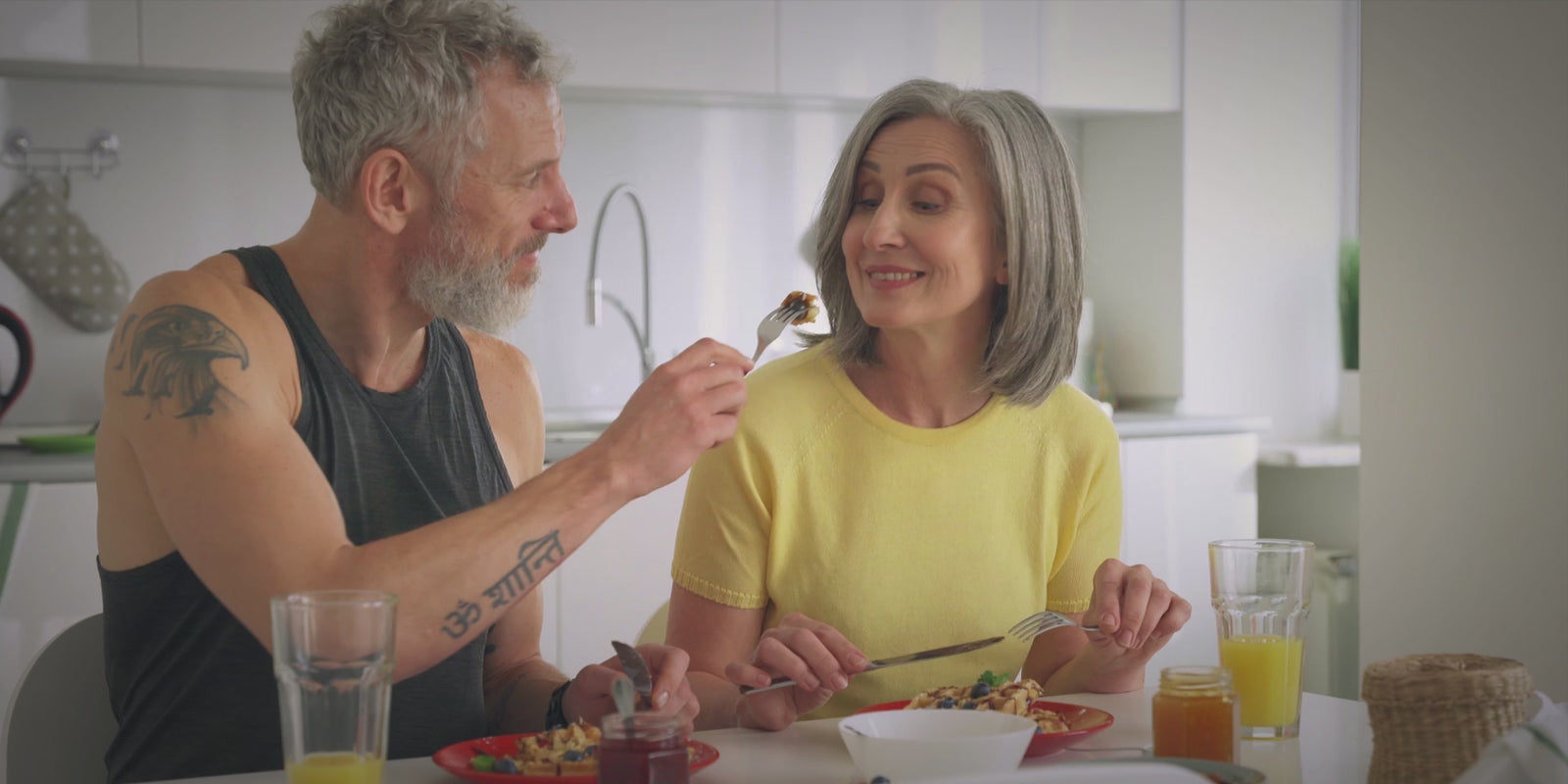 Vibe. Healthy couple in their 40s in a kitchen sharing healthy food with each other.